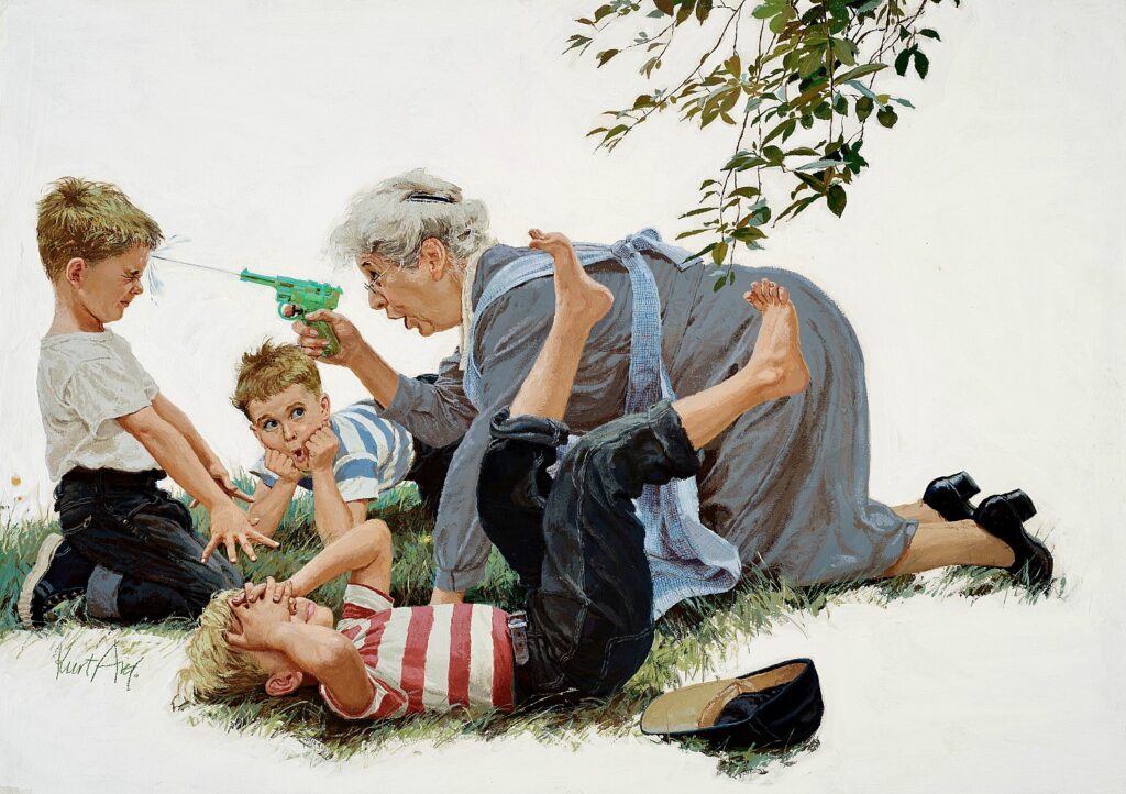 An older woman shooting a water gun into a little boy's face as two other little boys lay in the grass beside them.